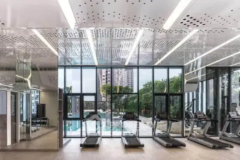 Modern gym with floor-to-ceiling windows overlooking a pool and cityscape.