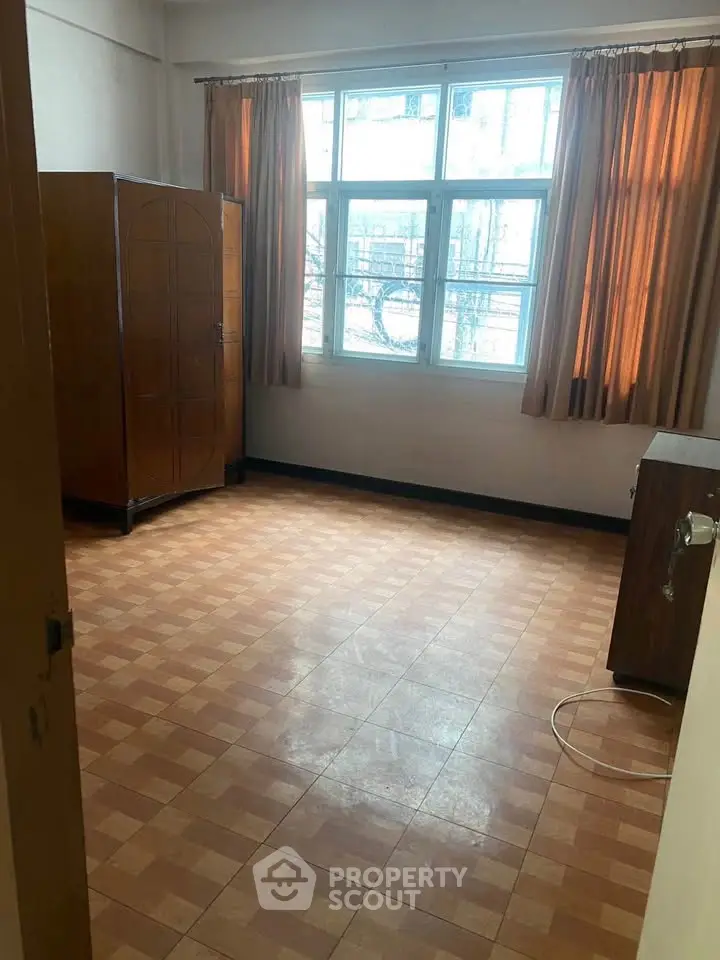 Spacious bedroom with large window and wooden wardrobe, perfect for natural light lovers.