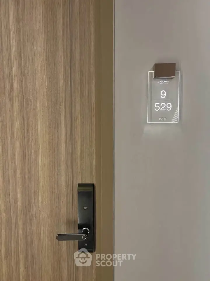 Modern apartment door with sleek electronic lock and room number display.