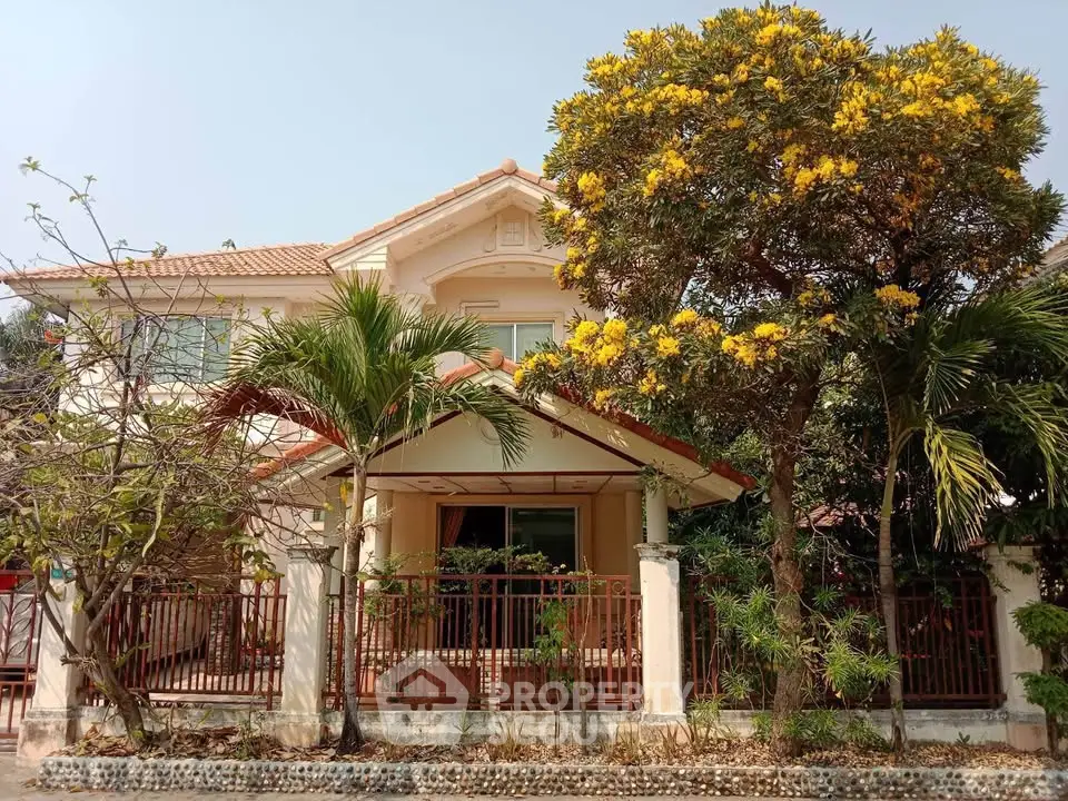 Charming two-story house with lush garden and blooming trees, perfect for family living.