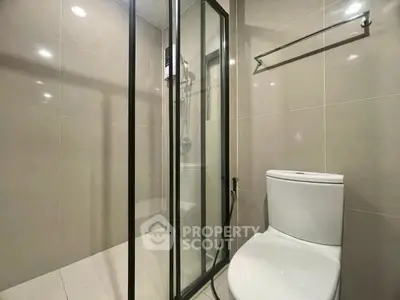 Modern bathroom with glass shower enclosure and sleek tile design.