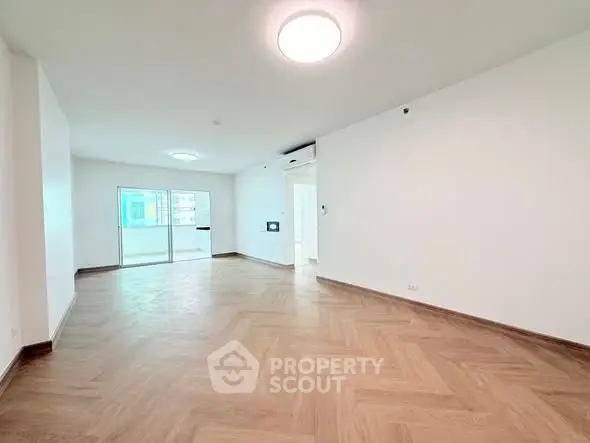 Spacious modern living room with wooden flooring and balcony access