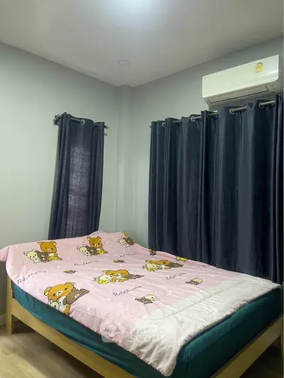 Cozy bedroom with cute character bedding and dark curtains, featuring air conditioning.