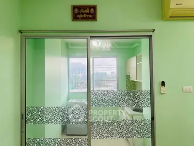 Modern kitchen with green walls and sliding glass door, featuring a compact layout.
