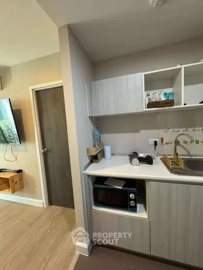 Modern compact kitchen with microwave and open shelving in cozy apartment