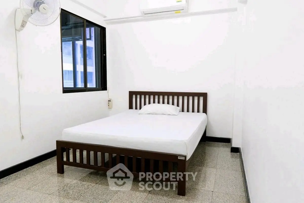 Minimalist bedroom with wooden bed frame and white walls, ideal for cozy living.