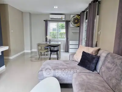 Modern living room with stylish furniture and dining area, featuring neutral tones and natural light.