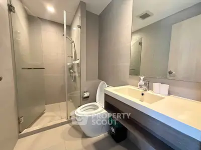 Modern bathroom with glass shower and sleek fixtures in contemporary apartment.