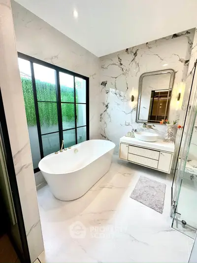 Luxurious marble bathroom with freestanding bathtub and large window view.