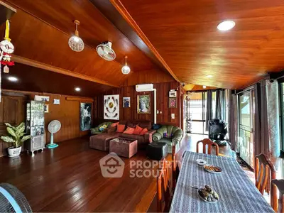 Spacious wooden living room with cozy seating and dining area, featuring warm lighting and decorative accents.