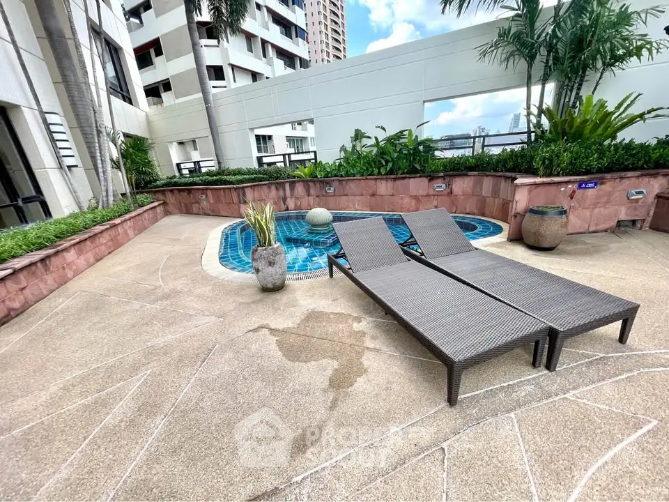 Luxurious rooftop pool area with stylish loungers and lush greenery in a modern high-rise building.