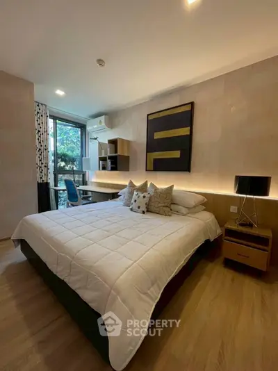 Modern bedroom with stylish decor and large window offering natural light