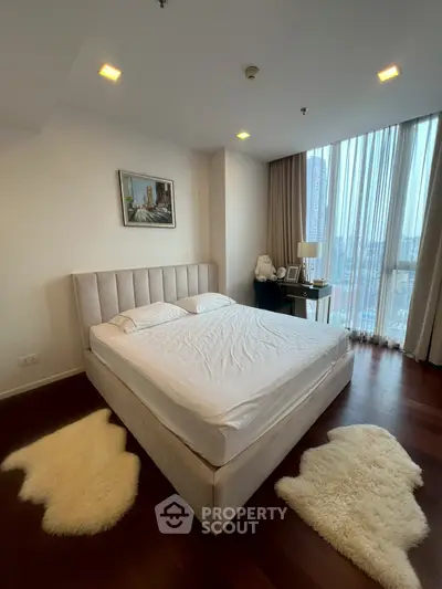 Luxurious bedroom with plush bed, elegant decor, and stunning city view through large windows.