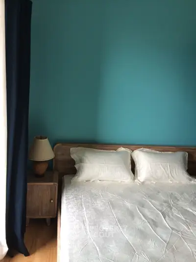 Cozy bedroom with teal accent wall and natural light