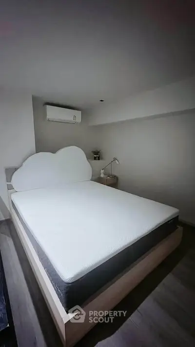 Cozy bedroom with unique cloud-shaped headboard and modern air conditioning unit.
