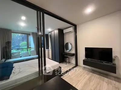 Modern bedroom with glass partition and sleek furnishings in urban apartment.