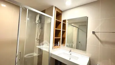 Modern bathroom with glass shower and sleek vanity in contemporary apartment.