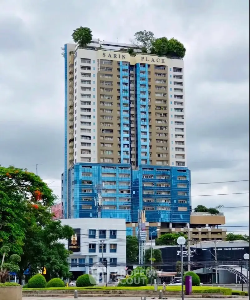Modern high-rise building with lush rooftop greenery and urban surroundings.