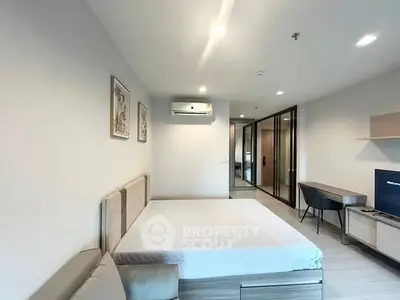 Modern bedroom with minimalist design and air conditioning, featuring a comfortable bed and sleek furniture.