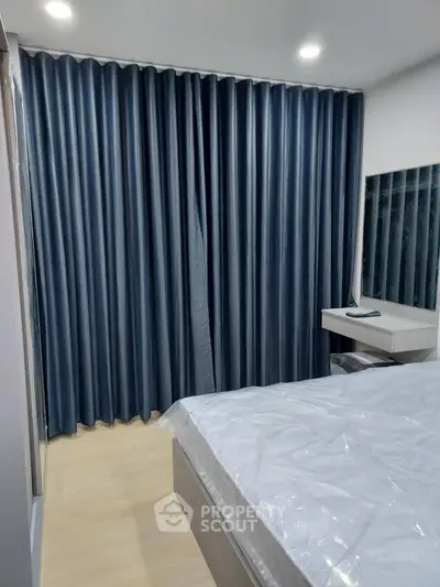 Modern bedroom with sleek design and dark curtains, featuring a cozy bed and stylish vanity mirror.