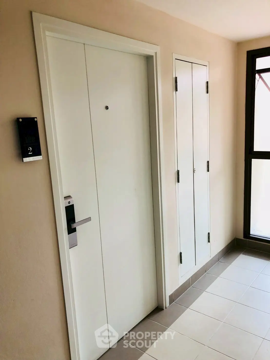 Modern apartment entrance with sleek white door and secure electronic lock.