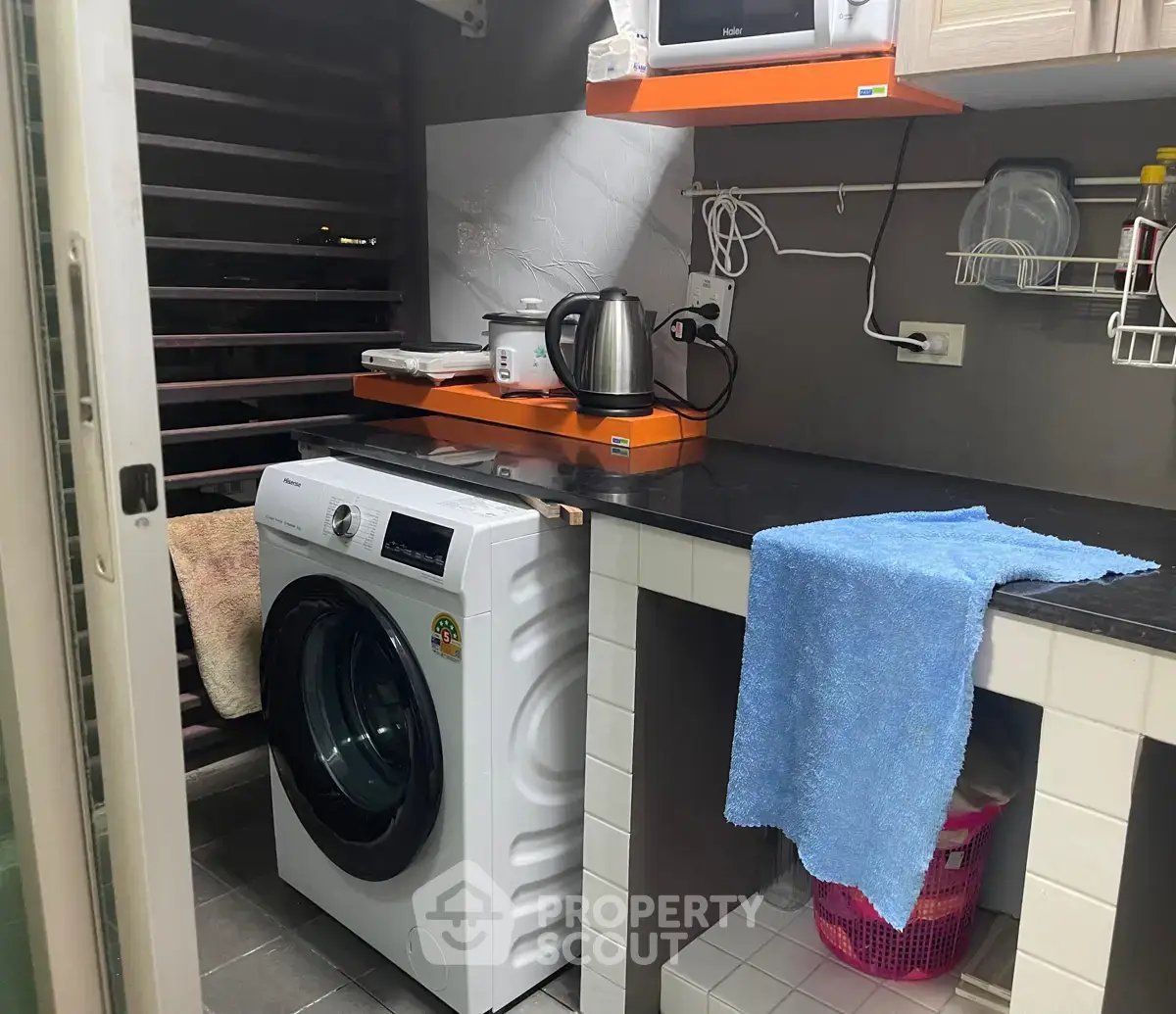 Compact laundry area with modern washing machine and countertop in cozy home setting.