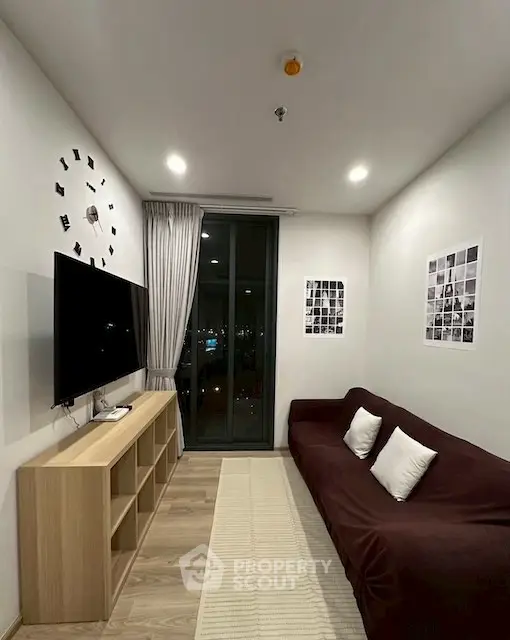 Modern living room with wall-mounted TV and city view through large window.