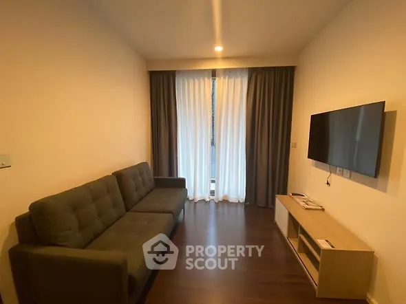 Modern living room with sleek sofa and wall-mounted TV, featuring elegant curtains and wooden flooring.