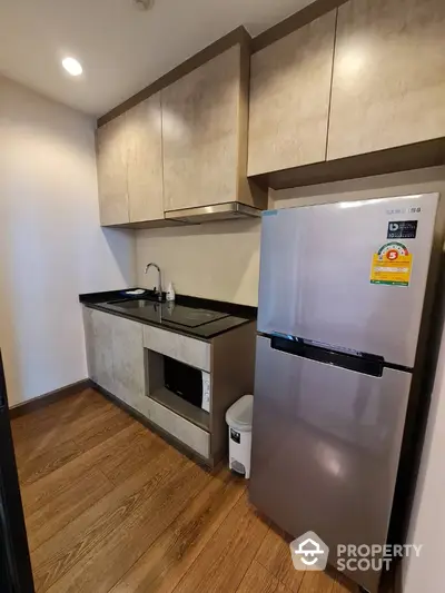 Modern compact kitchen with sleek cabinetry and stainless steel fridge