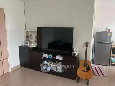 Cozy living room with modern TV setup and guitar, perfect for relaxation and entertainment.