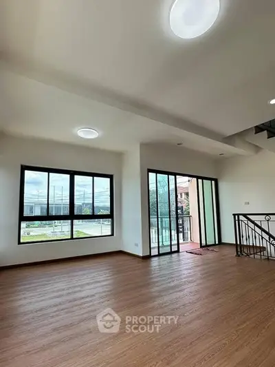 Spacious modern living room with large windows and balcony access.