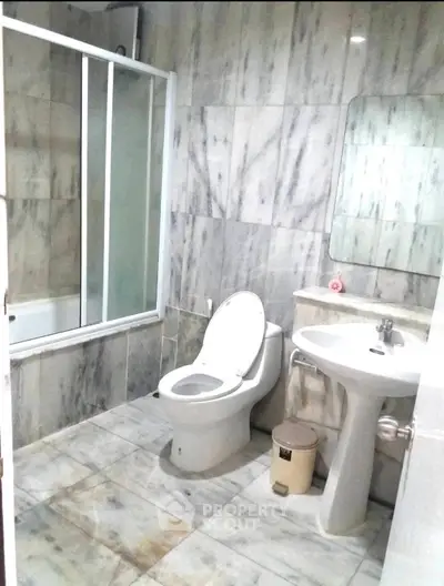 Modern bathroom with marble tiles and glass shower enclosure