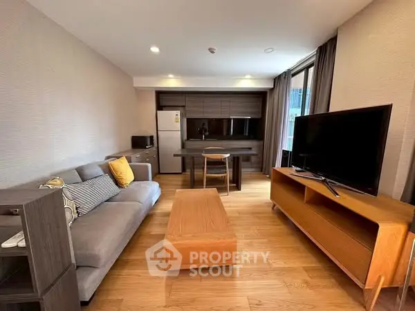 Modern living room with wooden flooring, sleek furniture, and a large TV, perfect for relaxation.