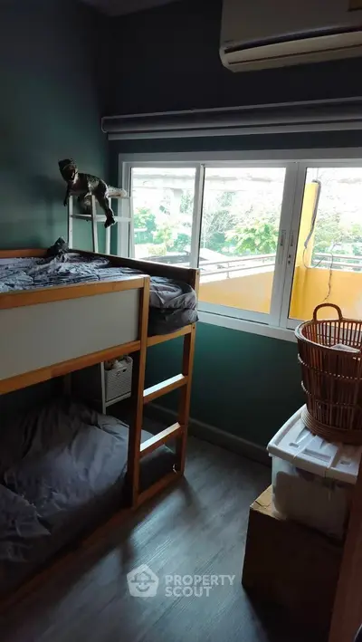 Cozy bedroom with bunk bed and large window overlooking greenery.