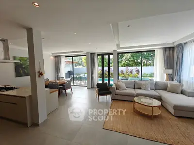 Spacious modern living room with open layout and pool view, featuring elegant decor and natural light.