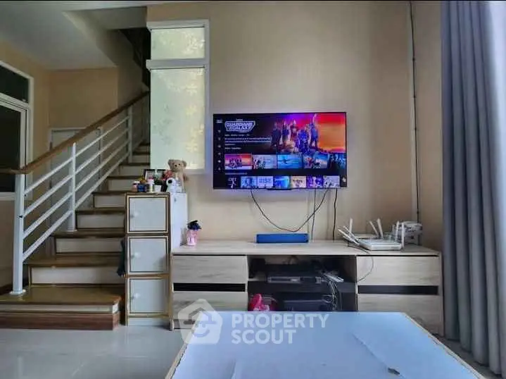 Modern living room with wall-mounted TV and stylish staircase
