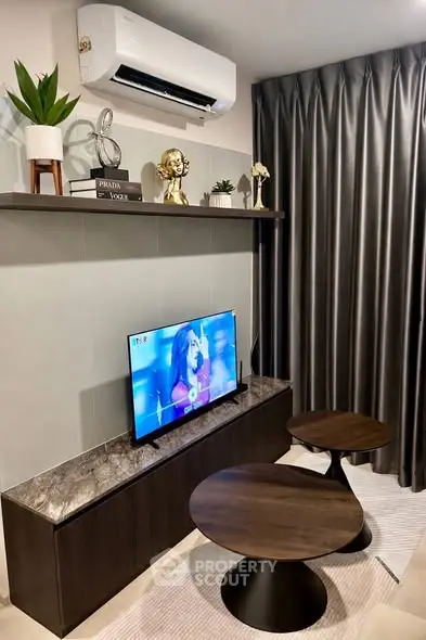 Modern living room with sleek furniture and wall-mounted TV, featuring stylish decor and air conditioning.