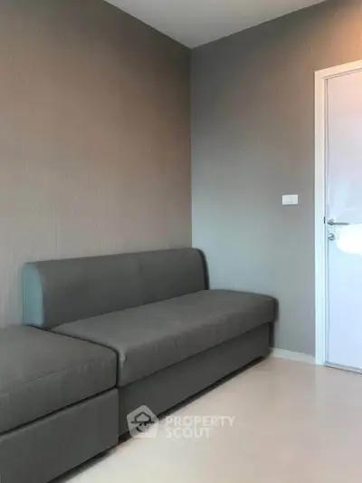 Modern minimalist living room with sleek gray sofa and neutral walls