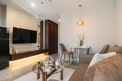 Modern living room with stylish decor, glass coffee table, and wall-mounted TV in a cozy apartment.