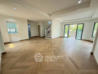 Spacious open-plan living room with elegant wood flooring and large windows