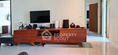 Modern living room with sleek wooden furniture and flat-screen TV, showcasing contemporary interior design.