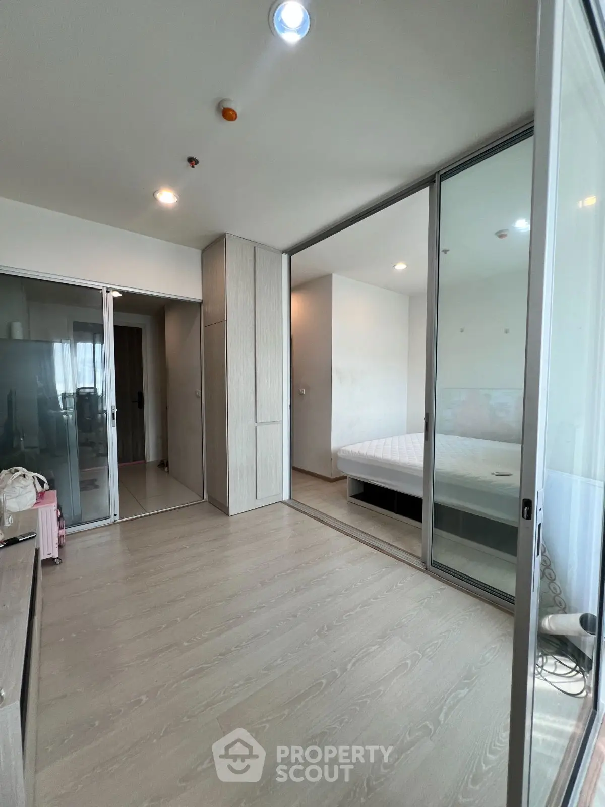 Modern bedroom with glass partition and wooden flooring in a stylish apartment.