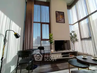 Modern living room with high ceilings, large windows, and stylish decor in a luxury apartment.