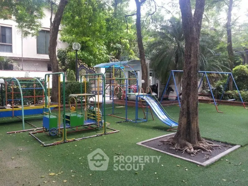 Charming residential playground with swings and slides surrounded by lush greenery.