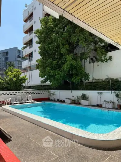 Charming outdoor pool area in a residential complex with lush greenery and modern architecture.