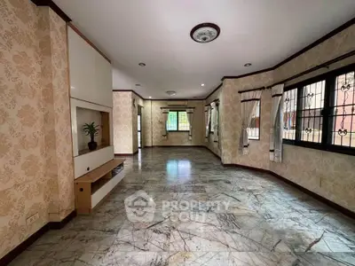 Spacious living room with elegant wallpaper and marble flooring, featuring large windows for natural light.