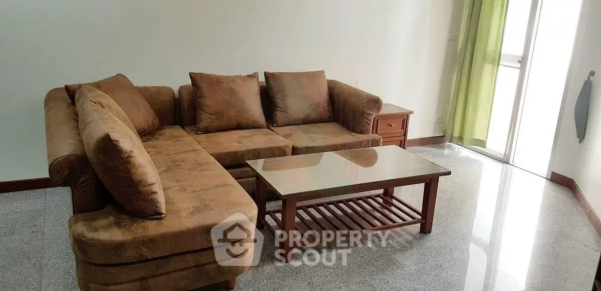 Spacious living room with cozy brown sectional sofa and glass coffee table, perfect for relaxation.