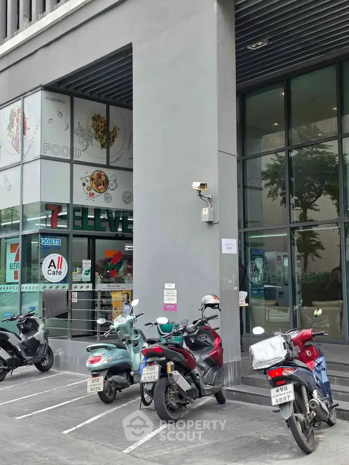 Modern commercial building exterior with parking and retail store entrance.