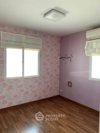 Charming empty bedroom with floral wallpaper and wooden flooring, perfect for personalization.