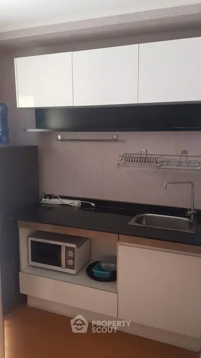 Modern compact kitchen with sleek cabinetry and built-in microwave, ideal for efficient cooking.